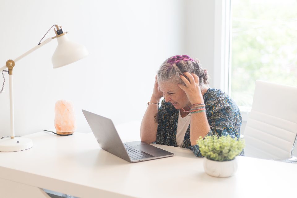 Femme stressée, la tête entre les mains devant son ordinateur