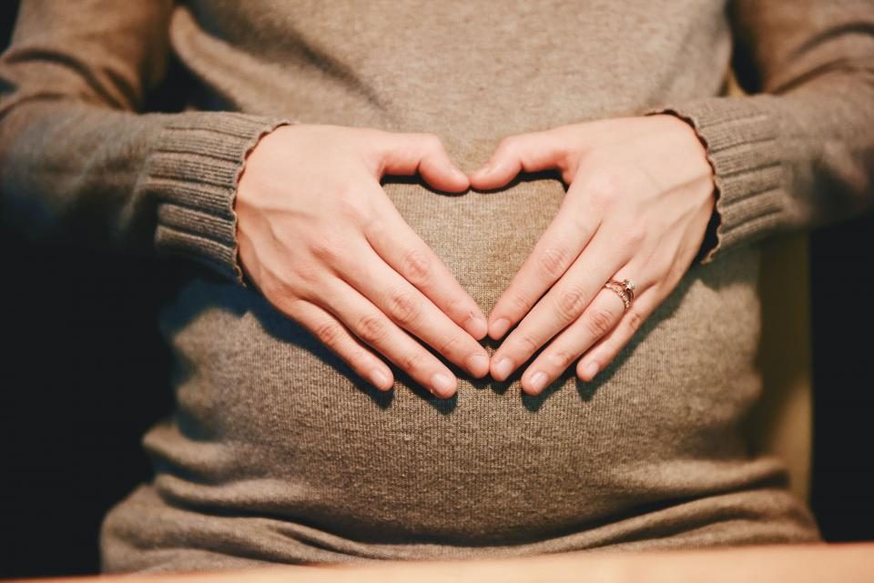 Femme enceinte formant un cœur avec ses mains sur son ventre