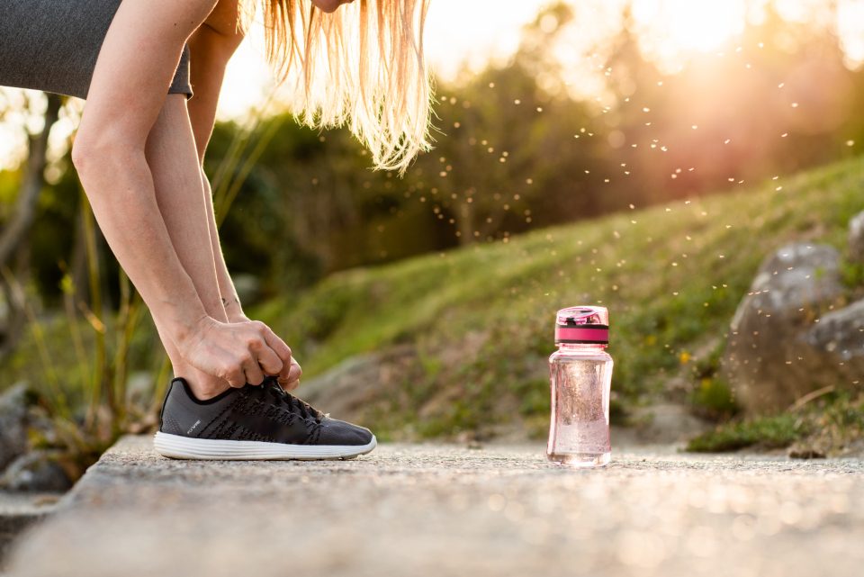 Sportive qui lace sa chaussure avant de courir au lever du soleil